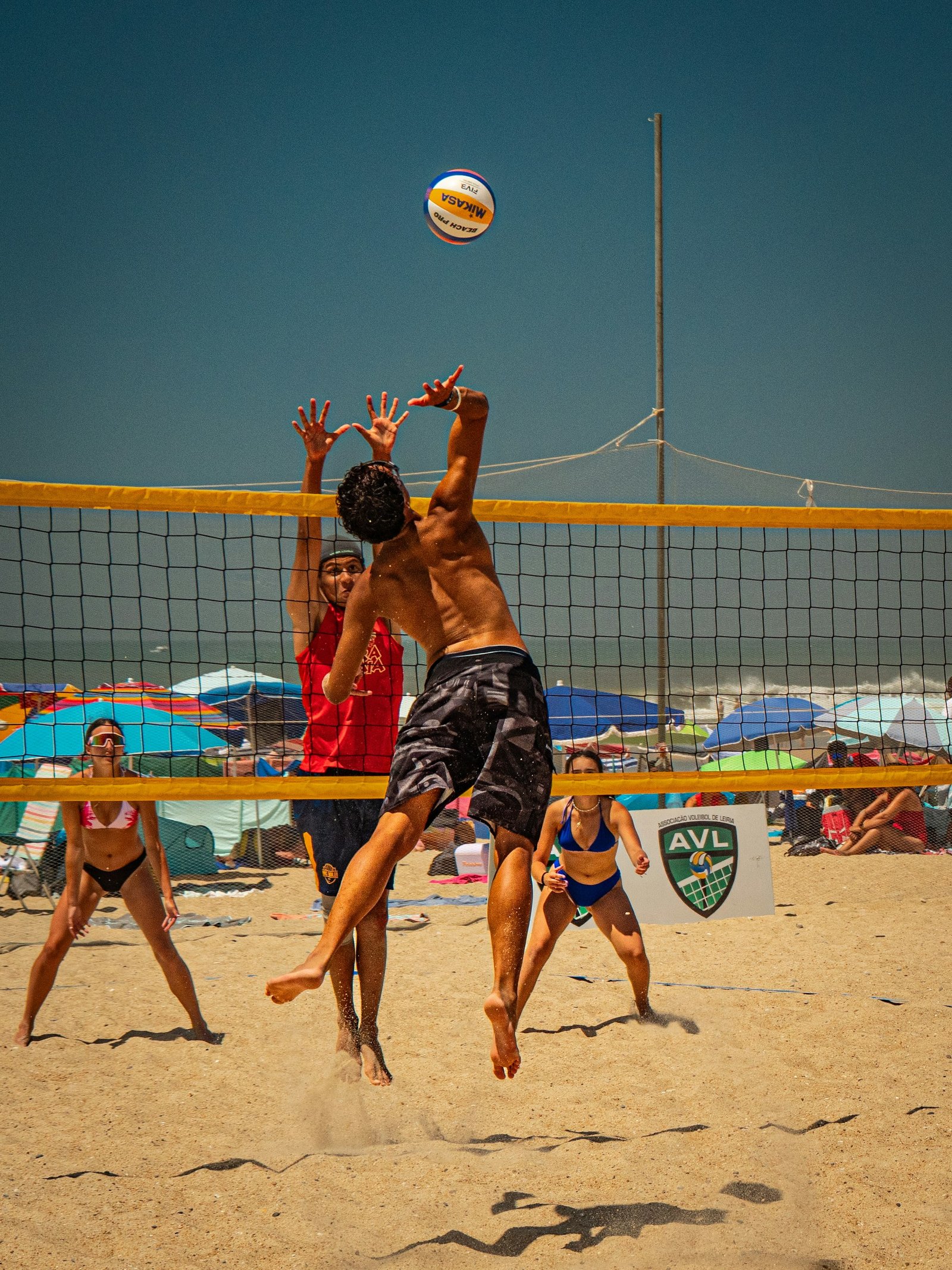 Dupla de vôlei de praia de uniforme amarelo caminhando na areia, com a rede ao fundo